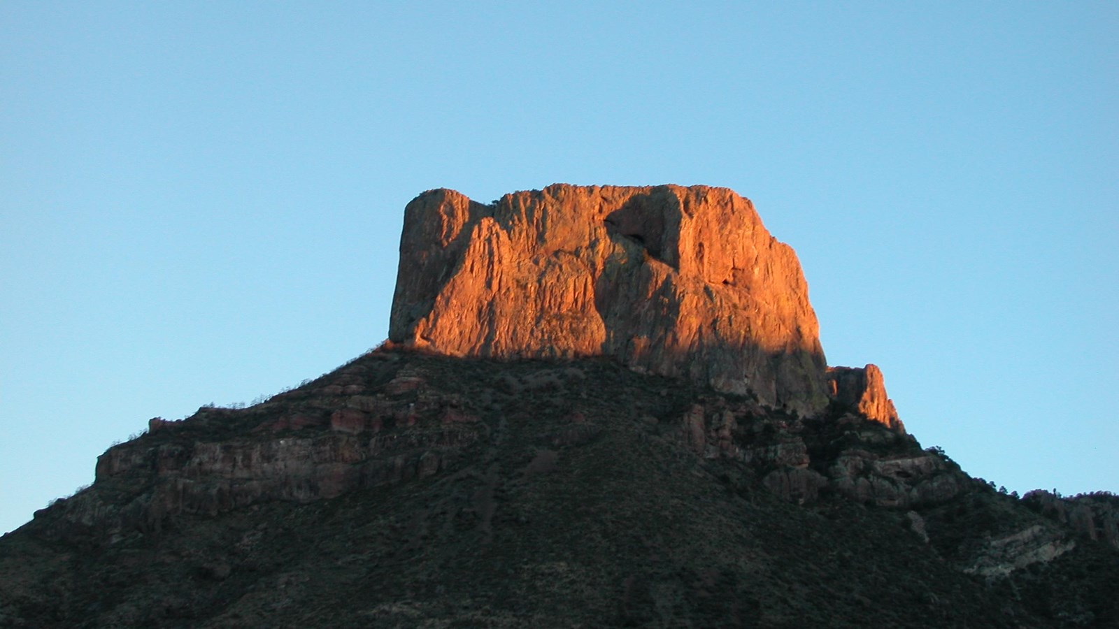 The setting sun highlights Casa Grande Peak, turning it a golden color.