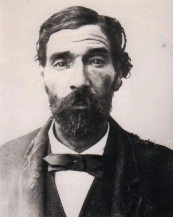 Black and white image of Mulato man, soulful dark brown eyes, mustache and beard, bow tie