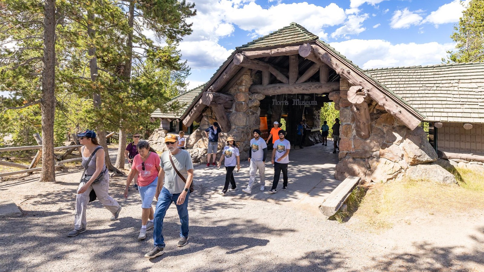 People walk through the breezeway of a historic building made of stone.