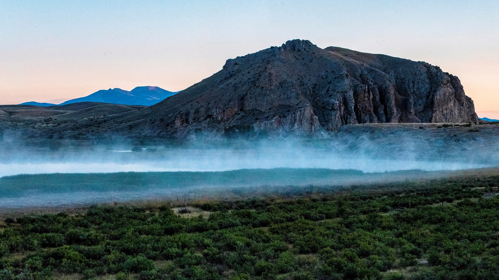 Rock outcropping above a river at sunrise, with fog hanging over the water.