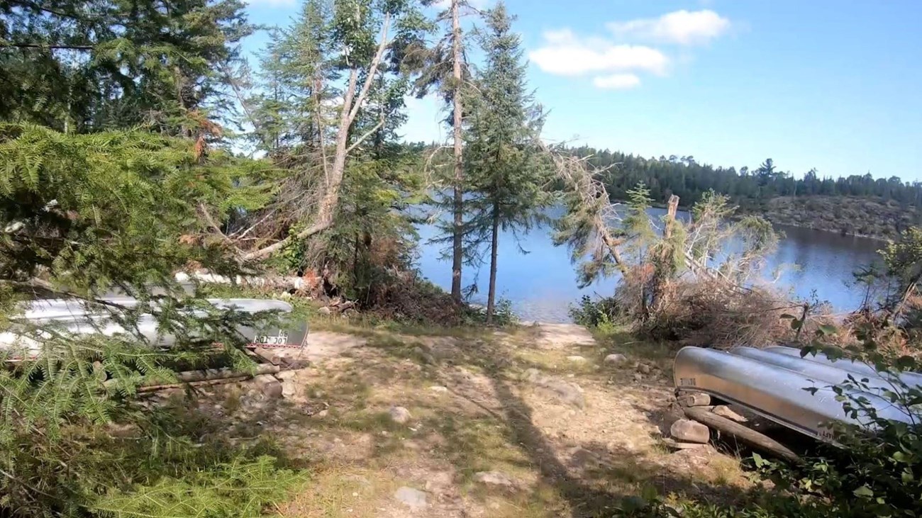 View of Locator Lake Trailhead at Locator Lake with Interior Lake Canoes next to shore.