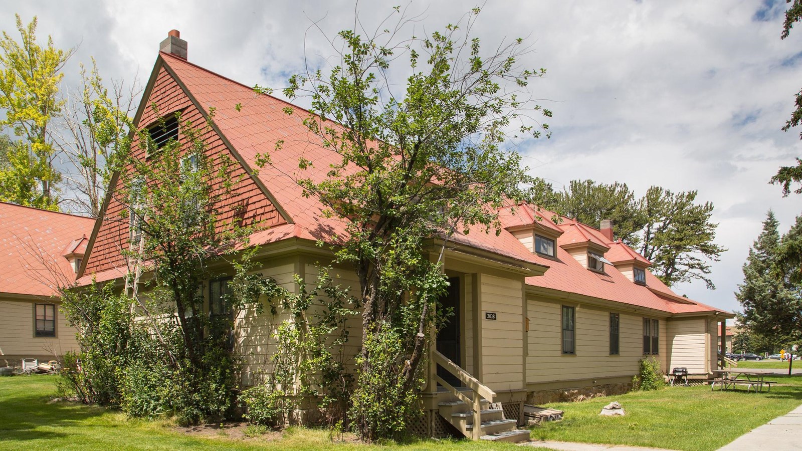 A historic building with pale yellow siding and a red shingle roof.
