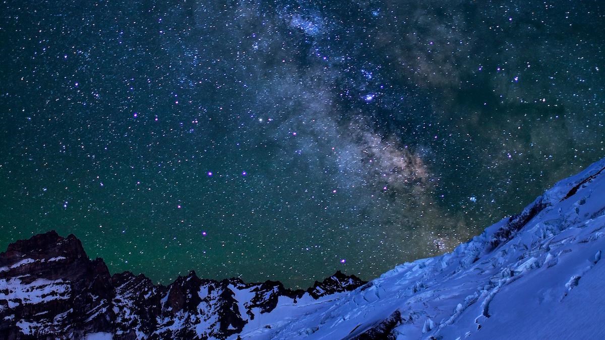Stars and milky way cover the sky above the glaciated ridges of Mount Rainier.