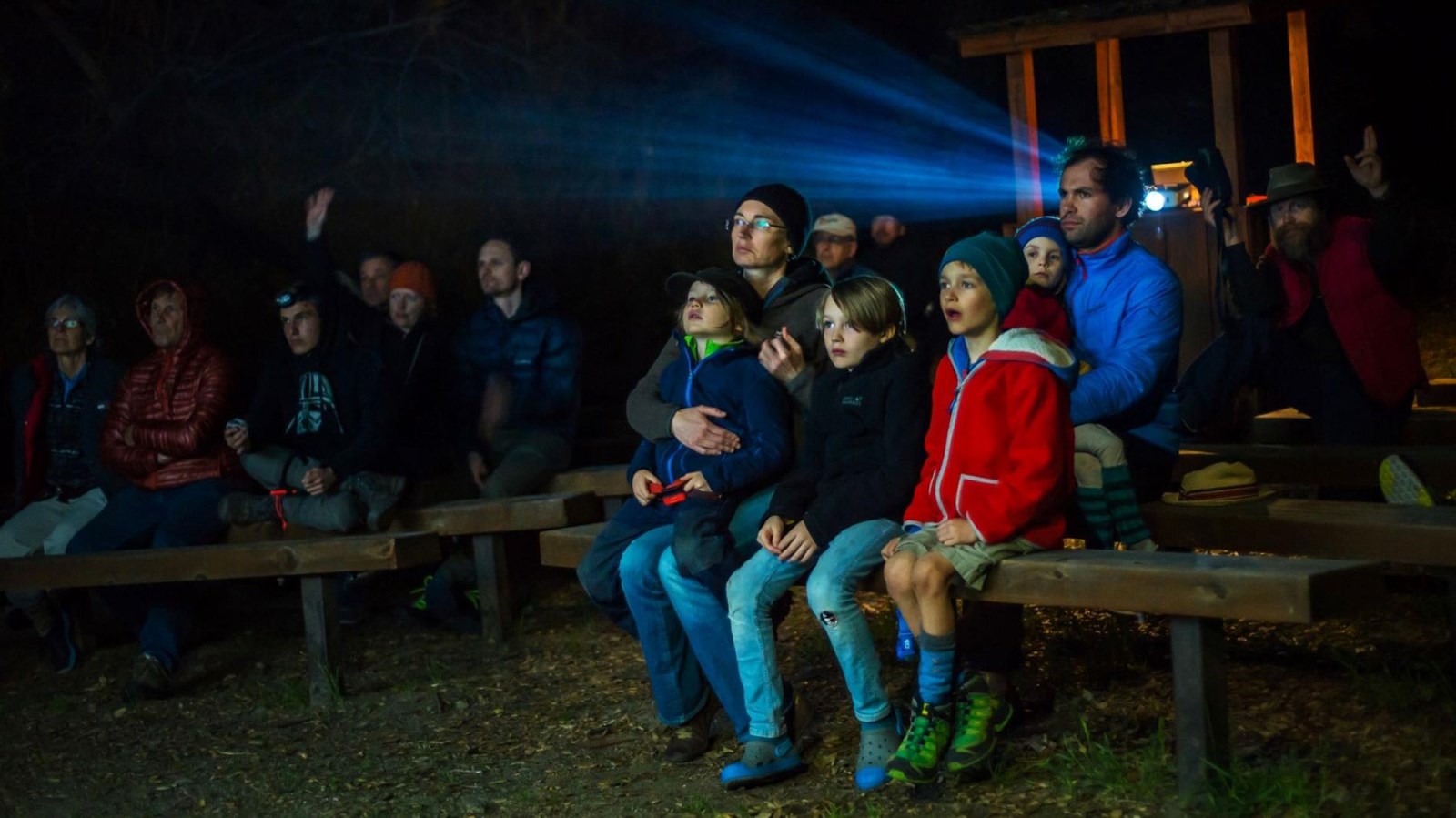 Families seated in rows while a projector lights up in the center isle