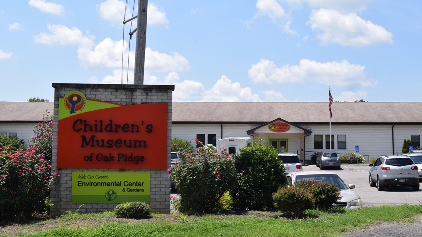 A brick sign reads “Children’s Museum of Oak Ridge” in front of a large school building.