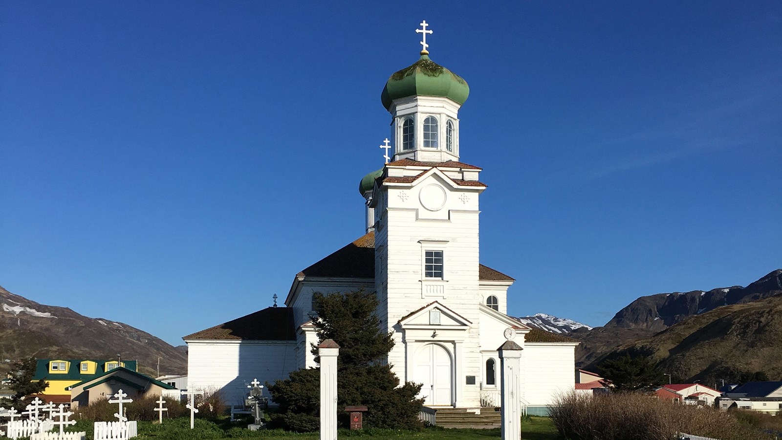 A white church with a green roof and traditional Russian Orthodox dome.