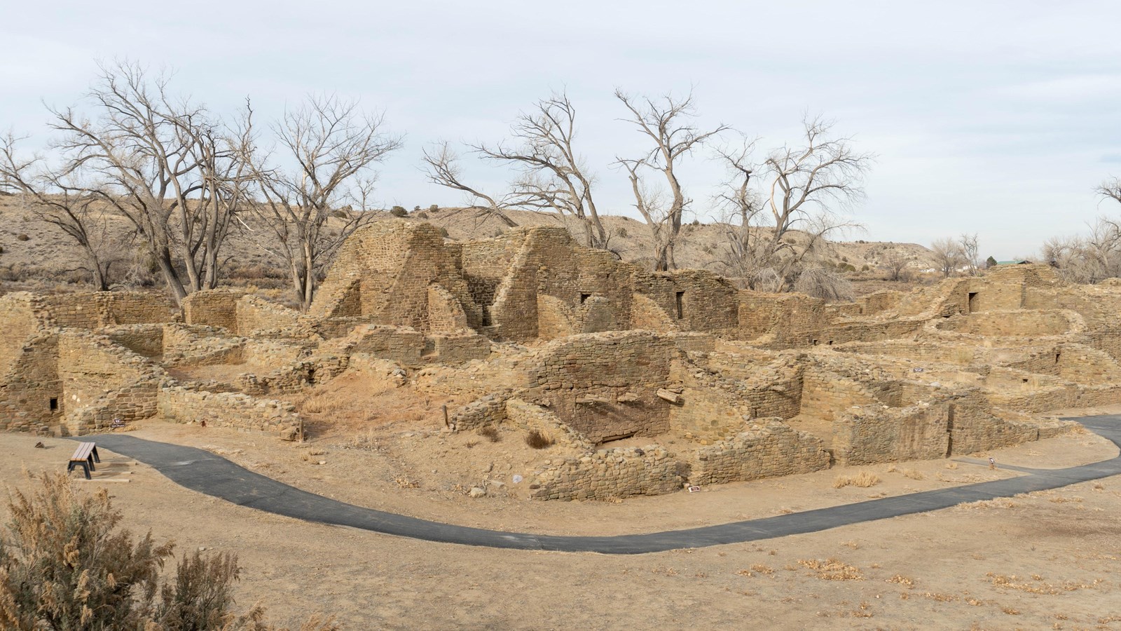 A black top trail runs along the foreground with an old looking, standstone structure in the back.