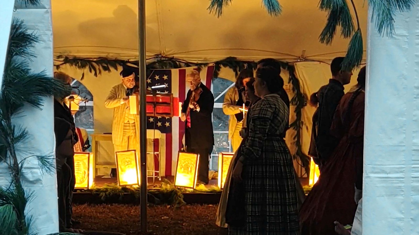 People in period clothing dance in the glow of lantern light.