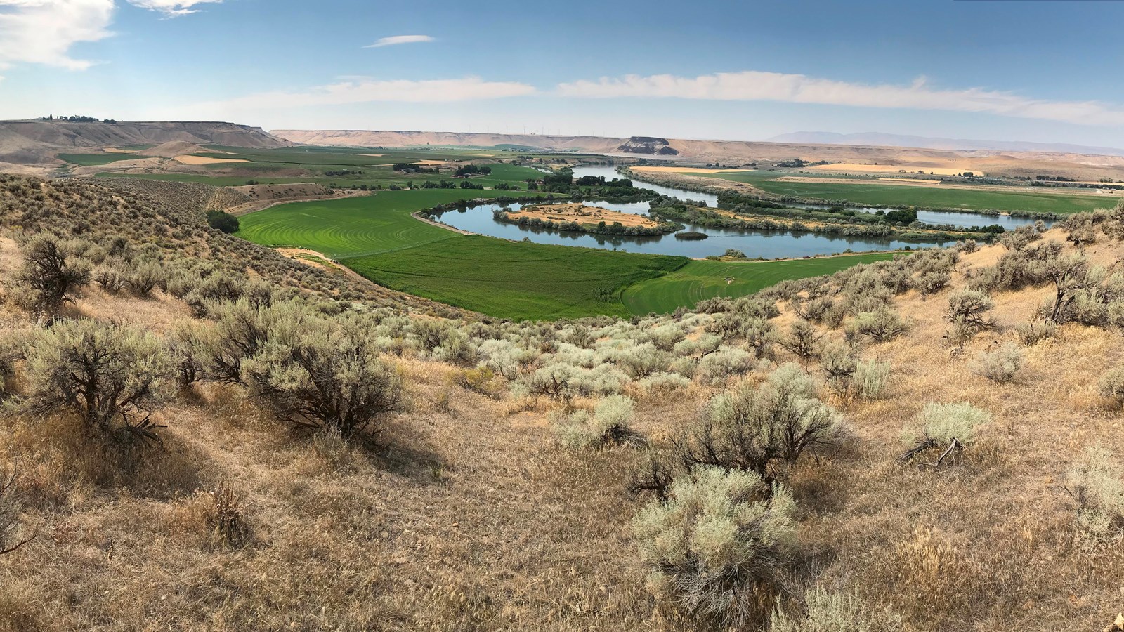 Looking out over a river valley with green grass and fertile fields.