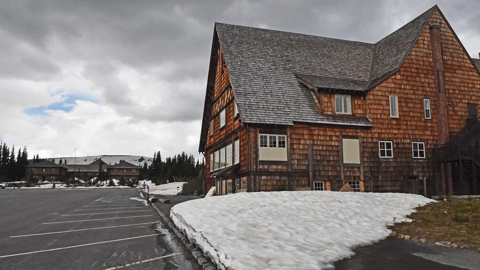 A three story rustic wooden building with patches of snow outside.