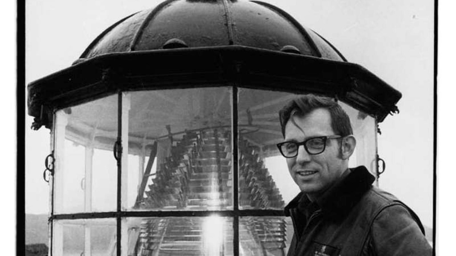 Man standing in front of glass prisms making up lighthouse lens.