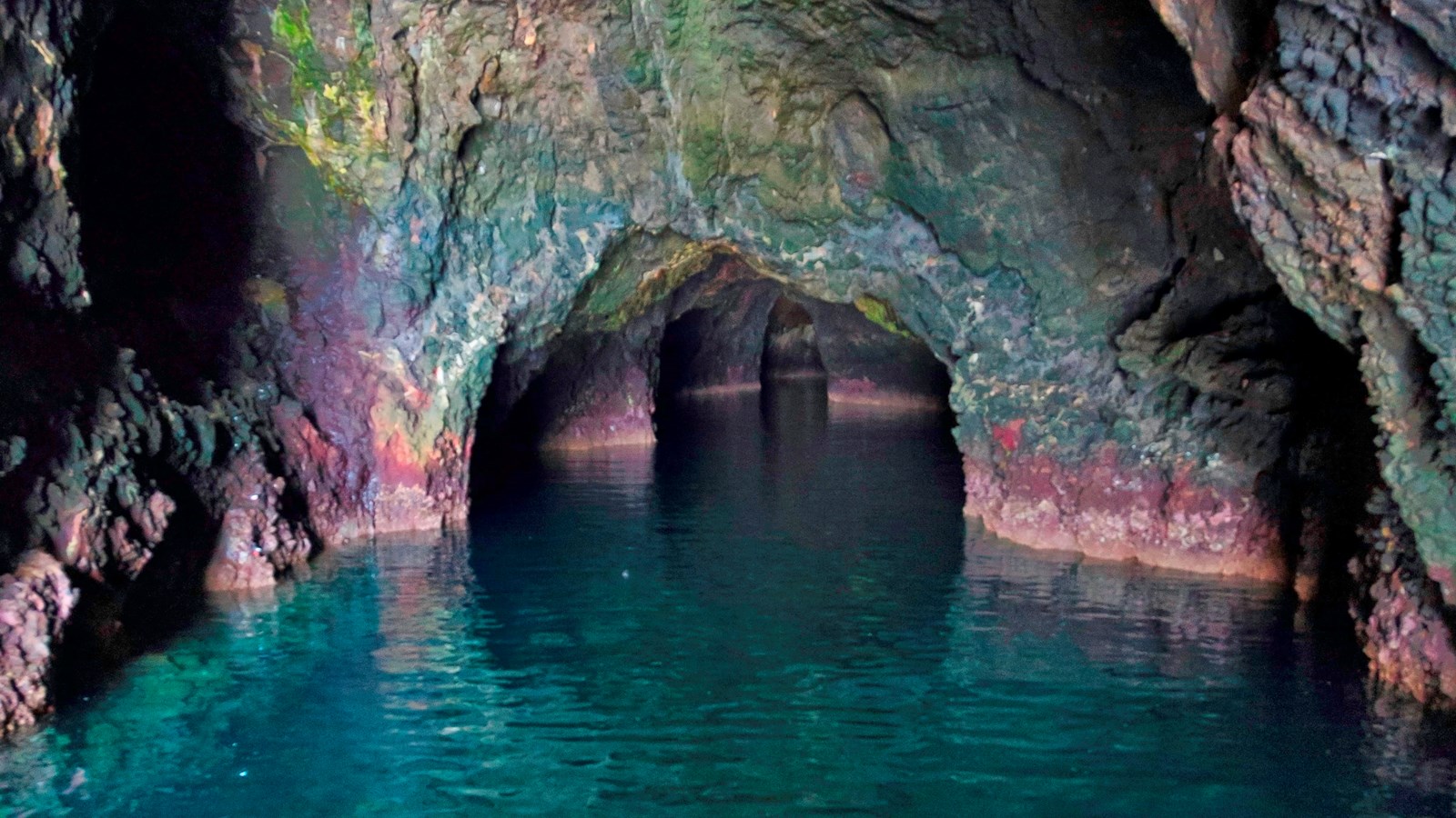 A large sea cave carved into steep volcanic cliffs. 