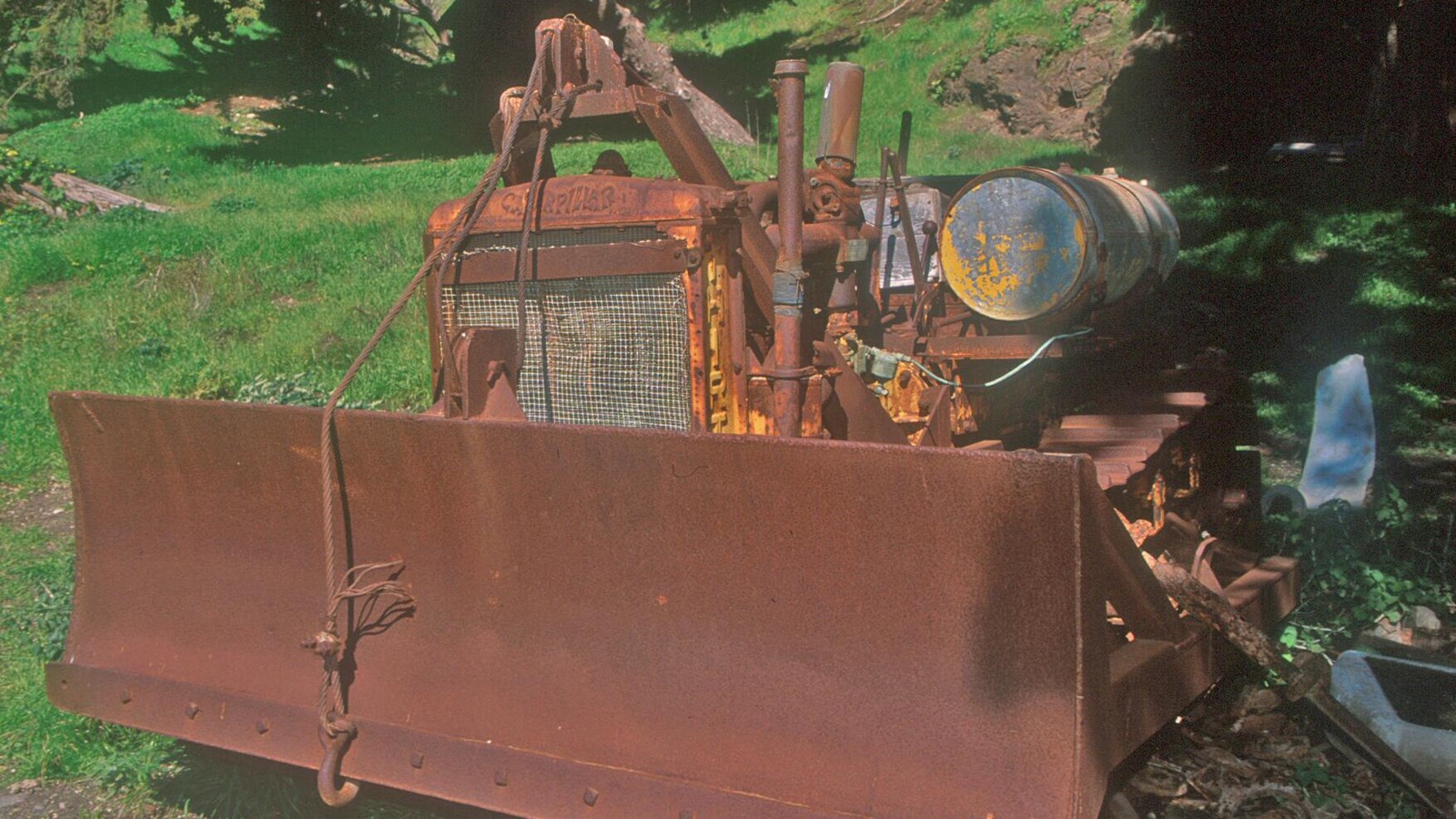 The grader frame has four metal wheels that house a long blade or shovel type attachment between the