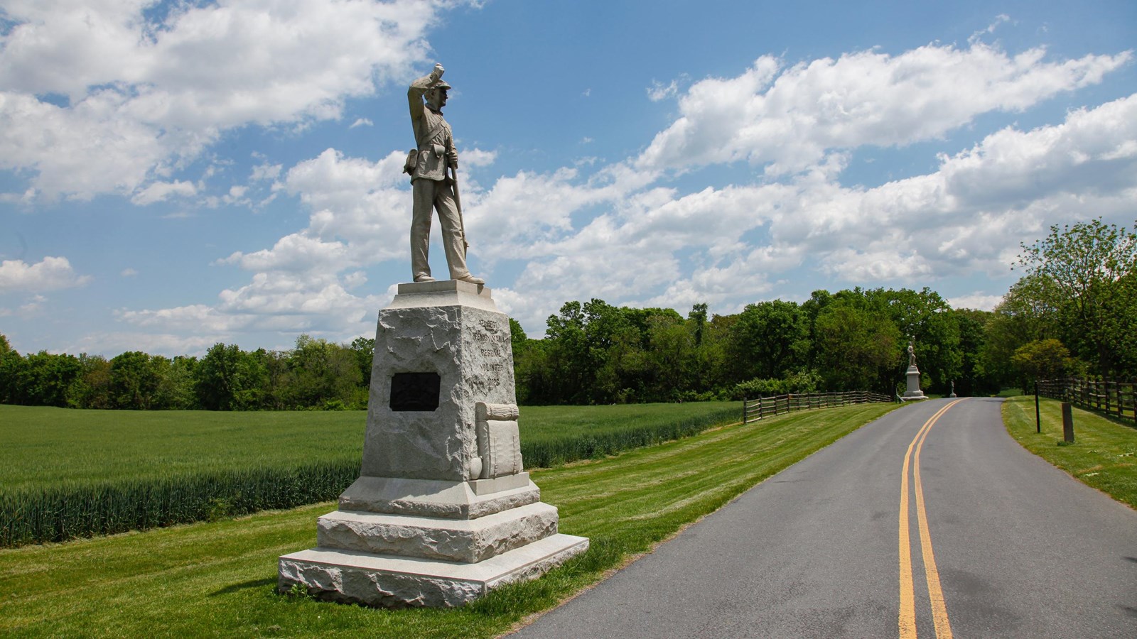 A monument of a soldier on the side of a road.