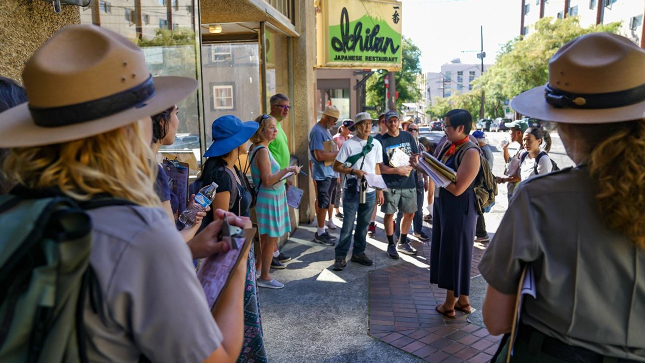 Rangers guiding and speaking to group on a city sidewalk.