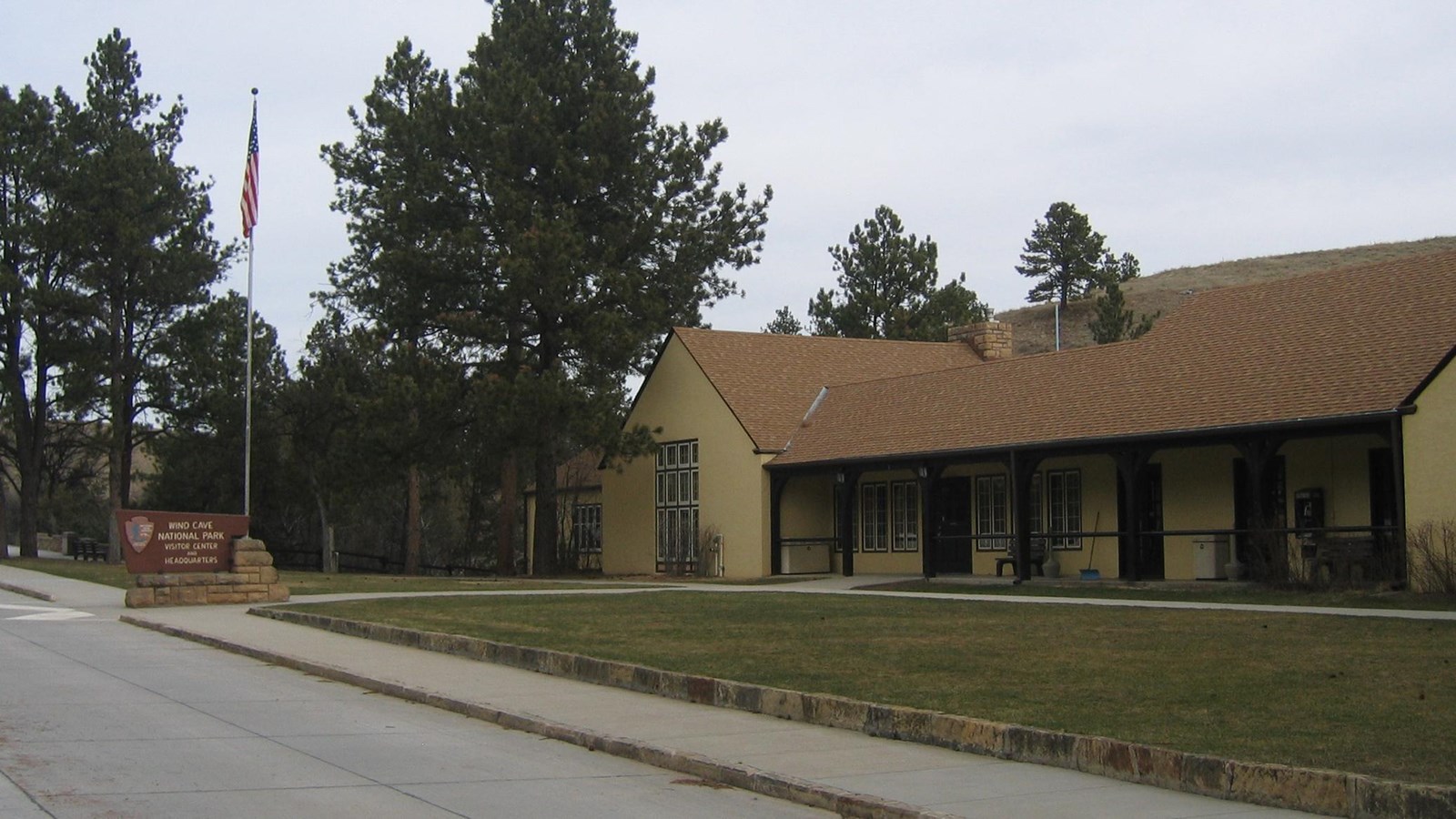 Looking at the front of the visitor center with the flag and stone park sign.