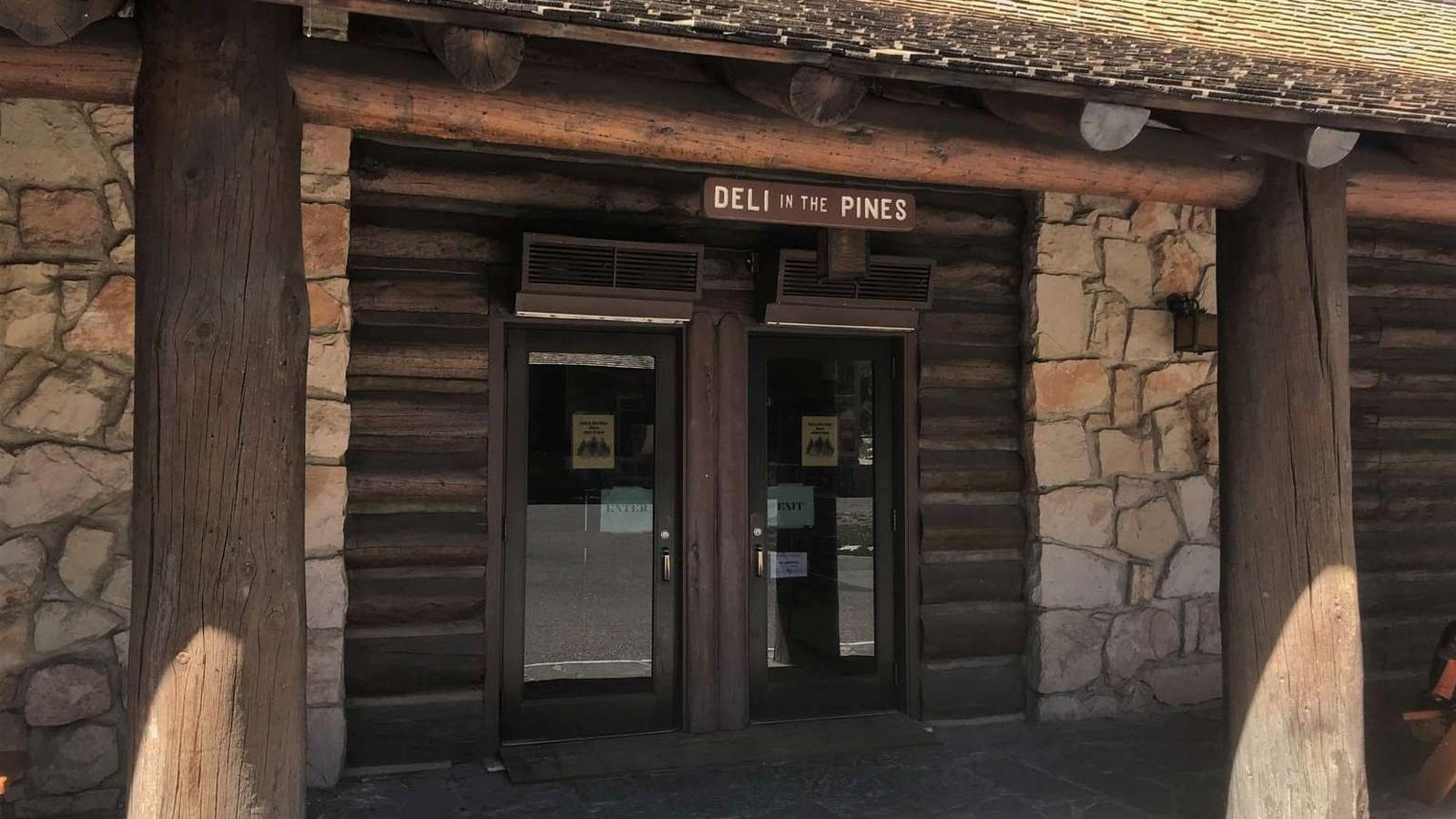 A stone building with a wood roof has a brown and sign over the door. 