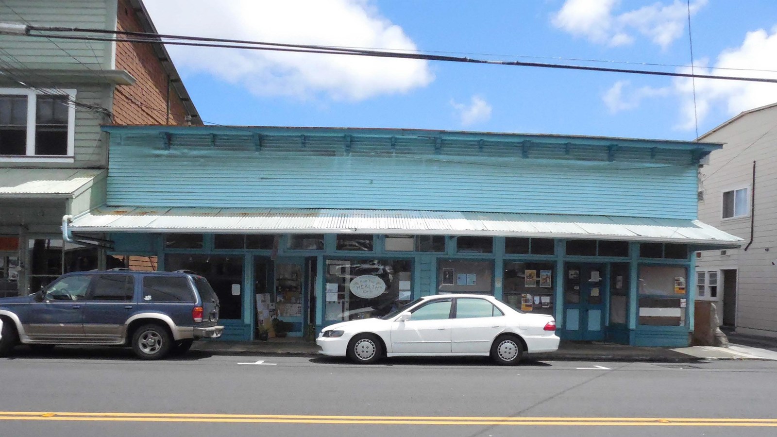 Commercial single story building on street with metal awning. 
