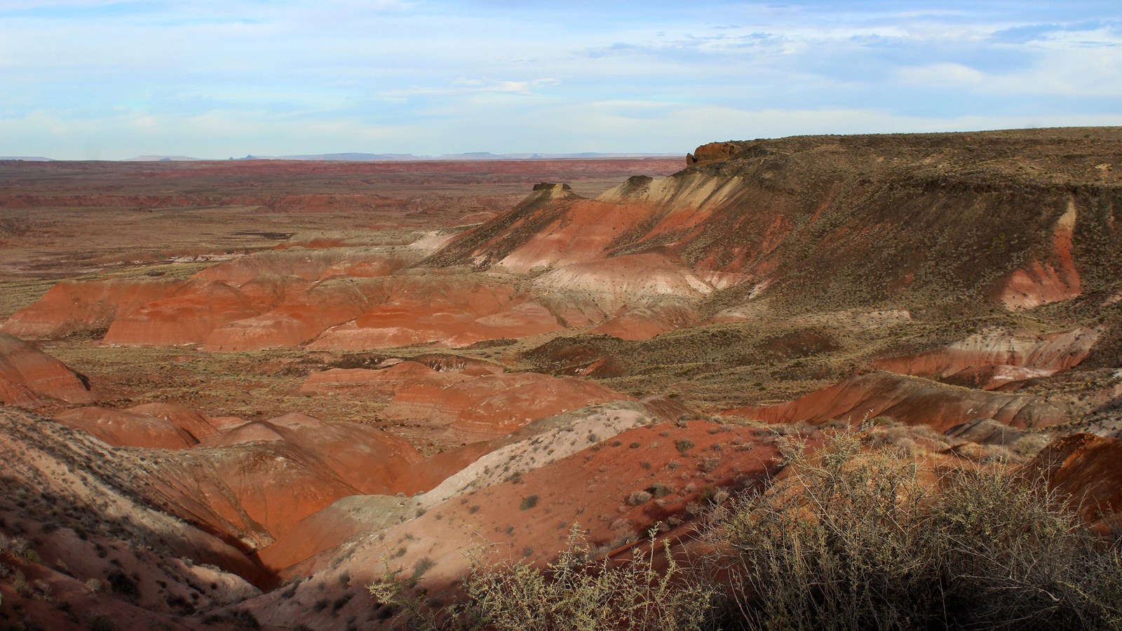 Red badlands topped by a capstone of black basalt in twilight.