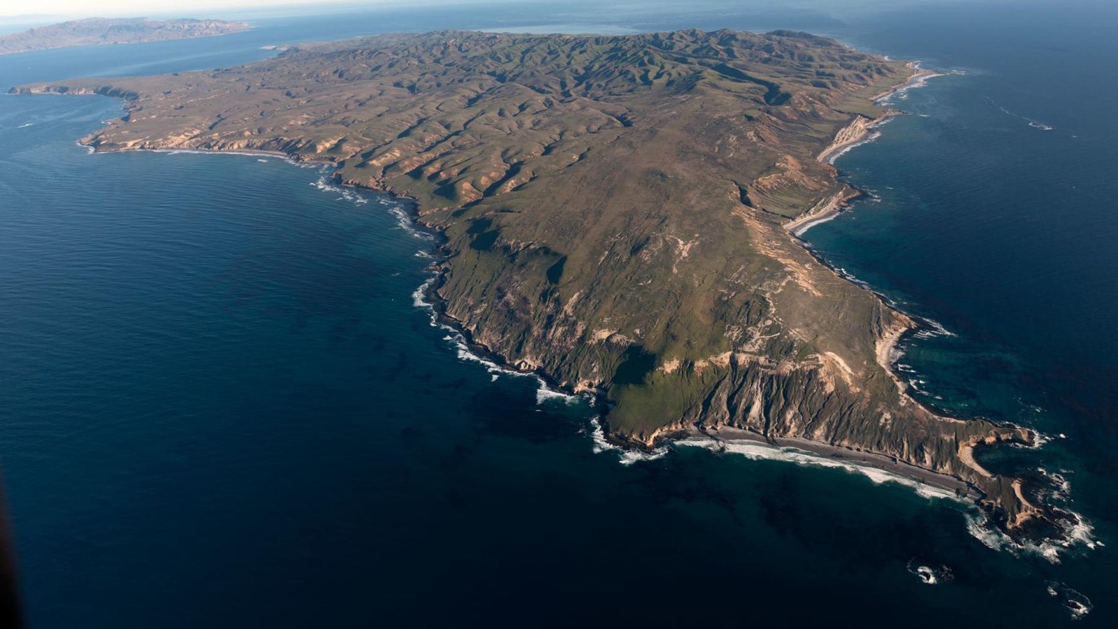 aerial image of large island with steep cliffs 