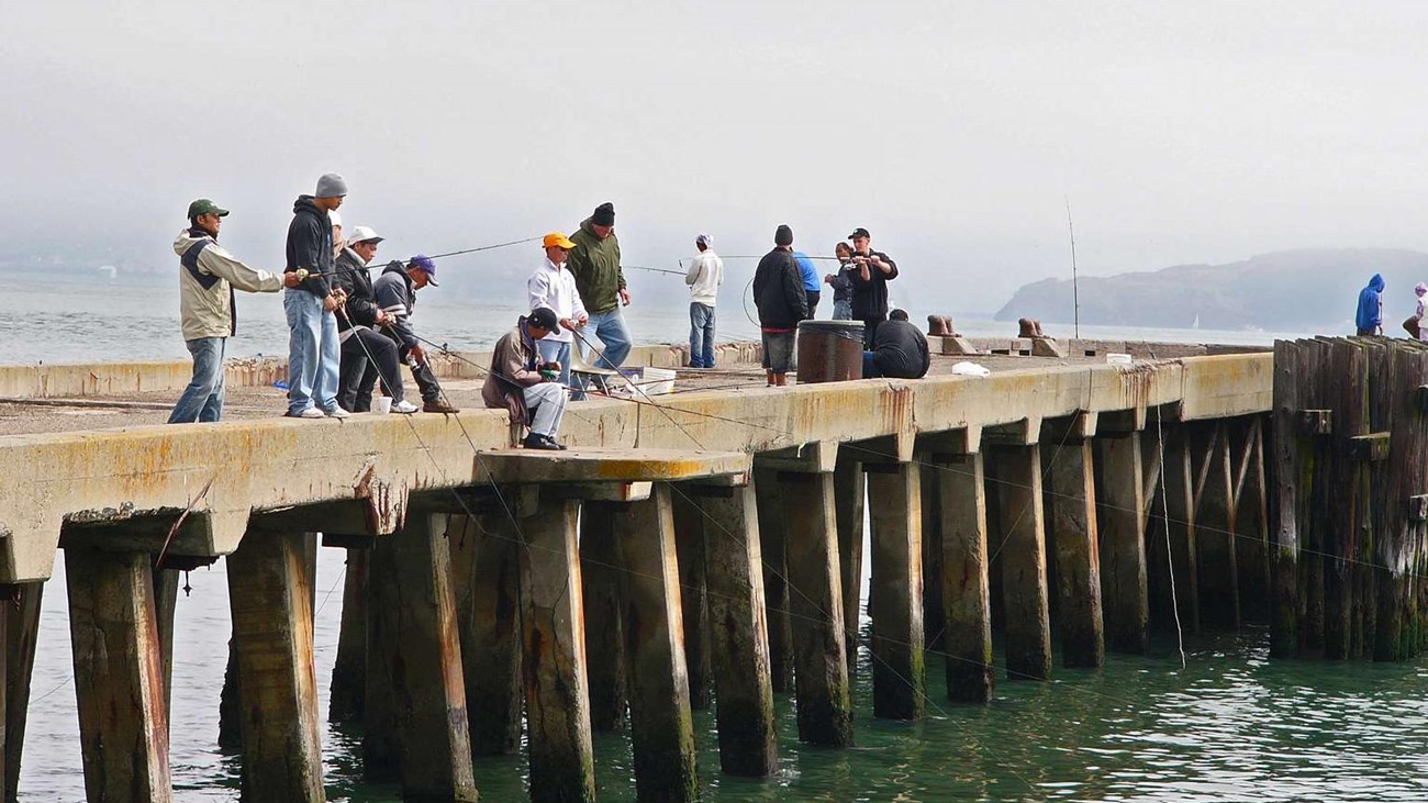 Visitors standing on a pier with fishing poles.