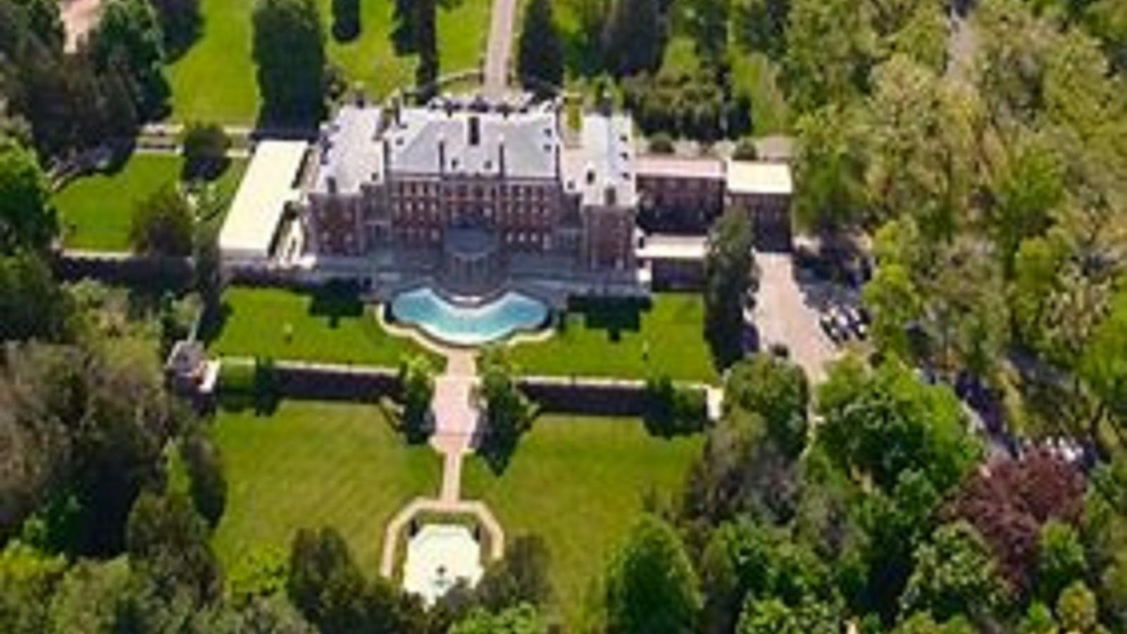 Aerial view of large home with garden in back with shrubs as barrier and paths in straight lines.