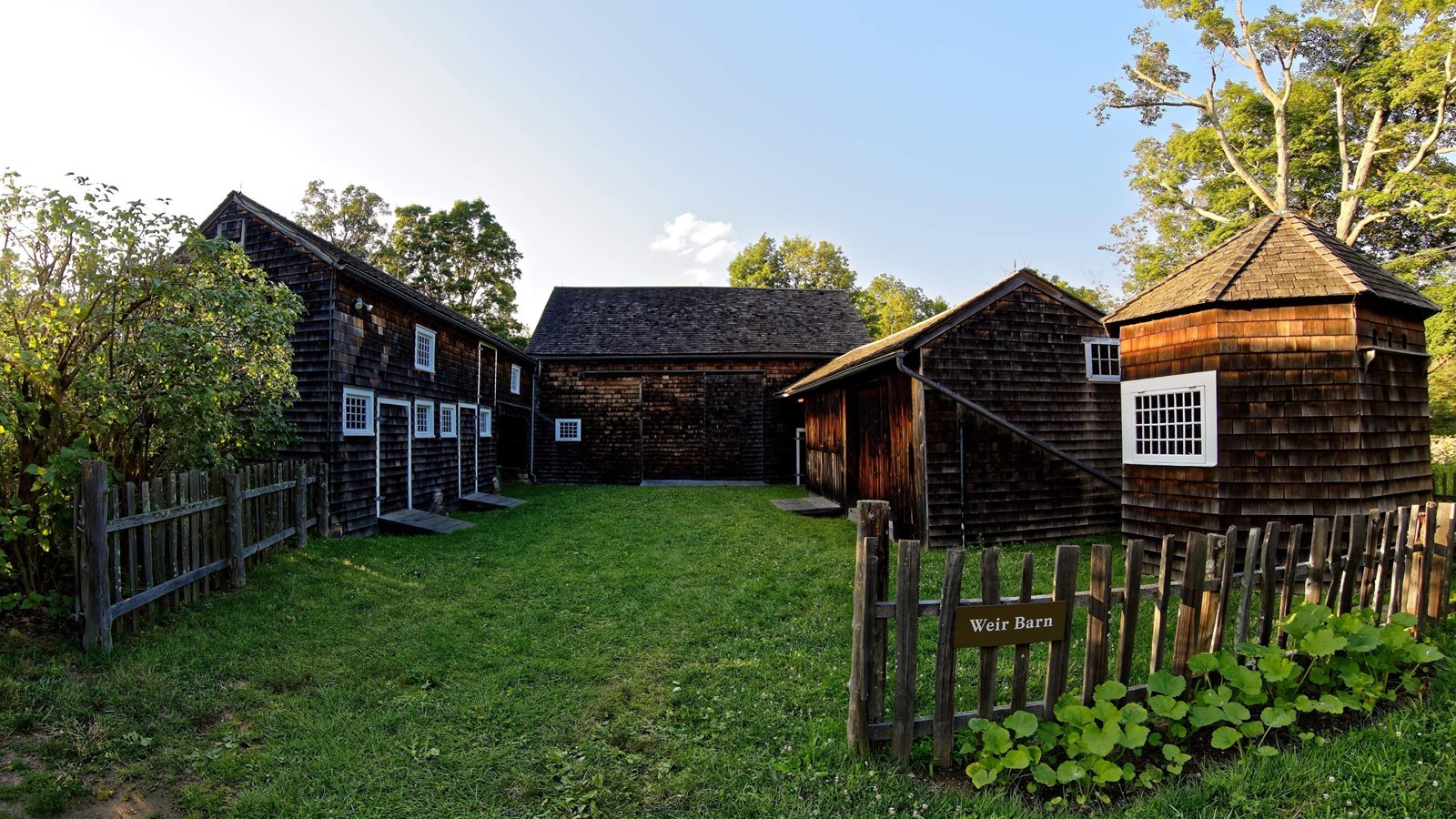 A wooden barn with a fence line around it.