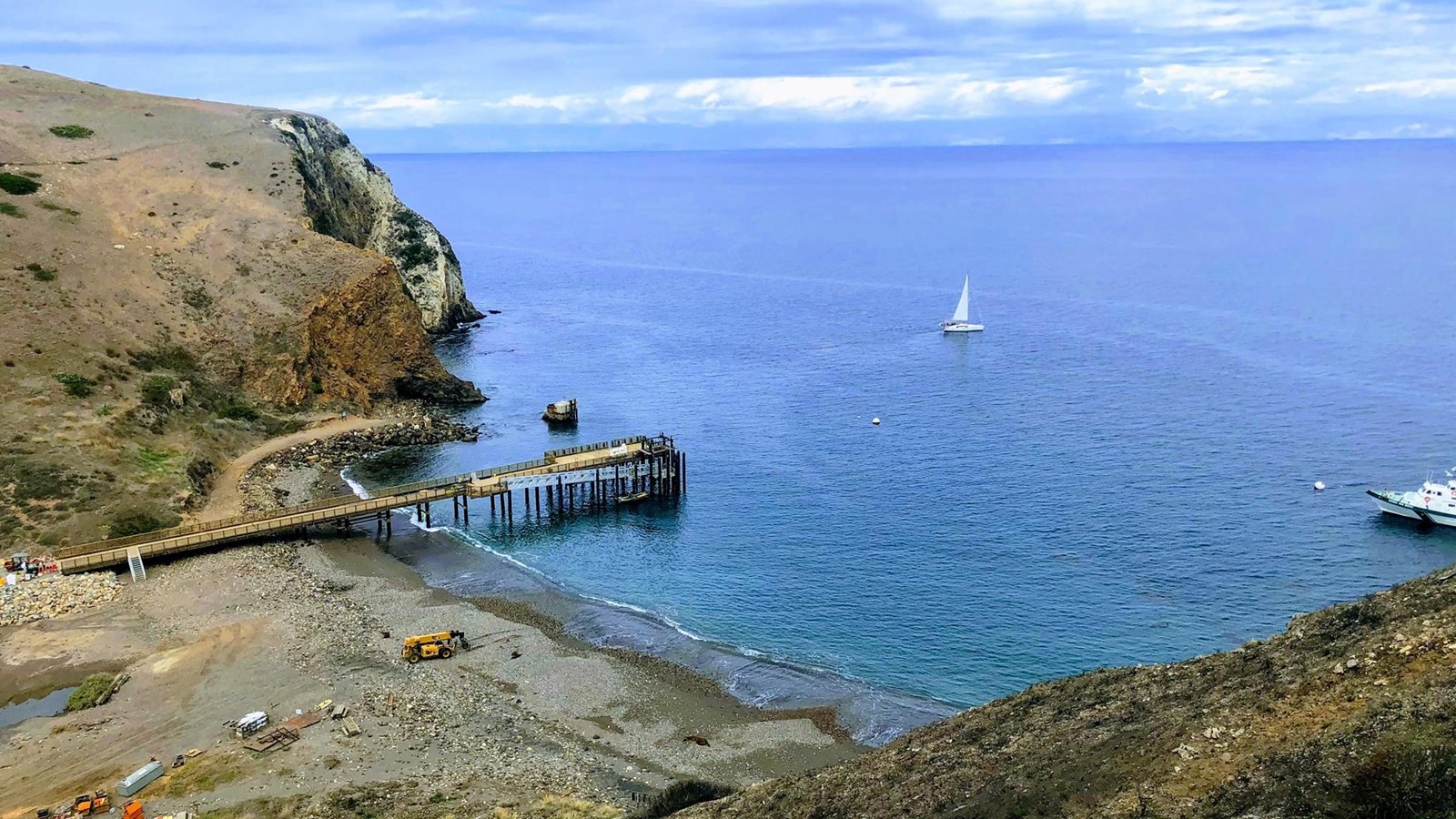 large pier in small anchorage with rocky beach.