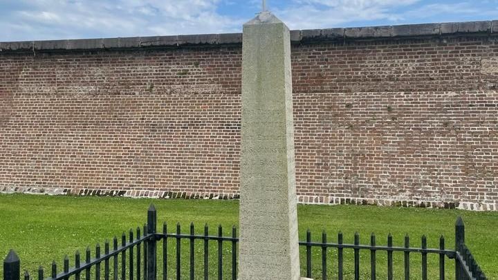 A small gray obelisk dedicated to the USS Patapsco is surrounded by metal fencing.