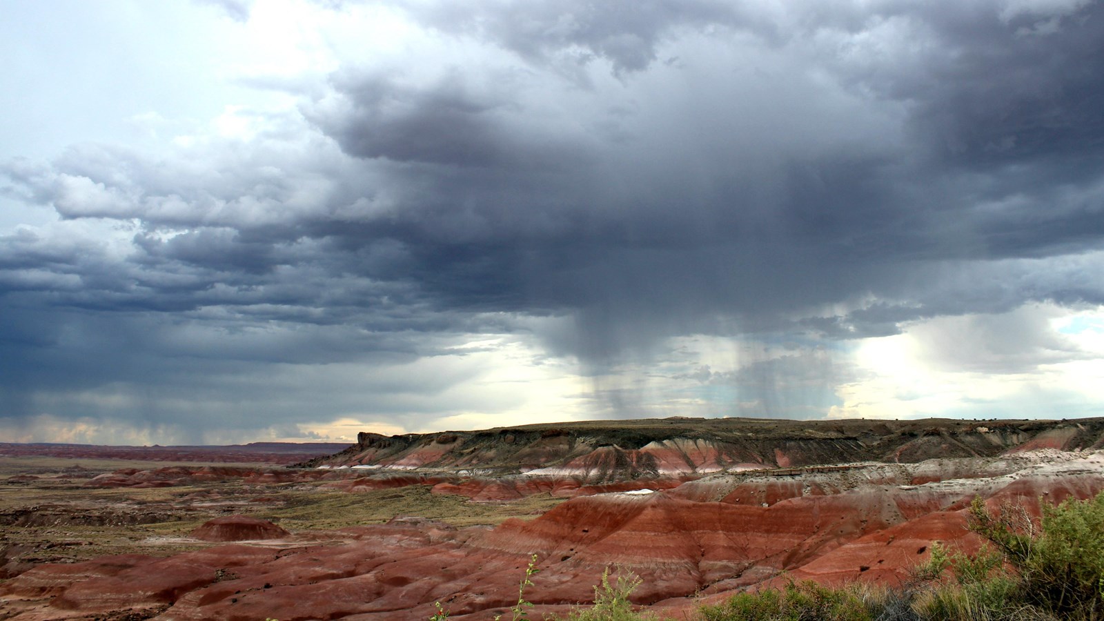 Red badland topography under a stormy sky.