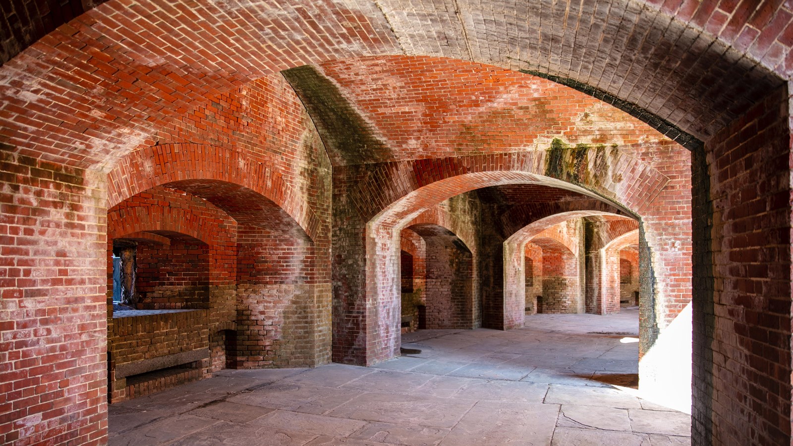 Red brick arches support the lower level of a fort.