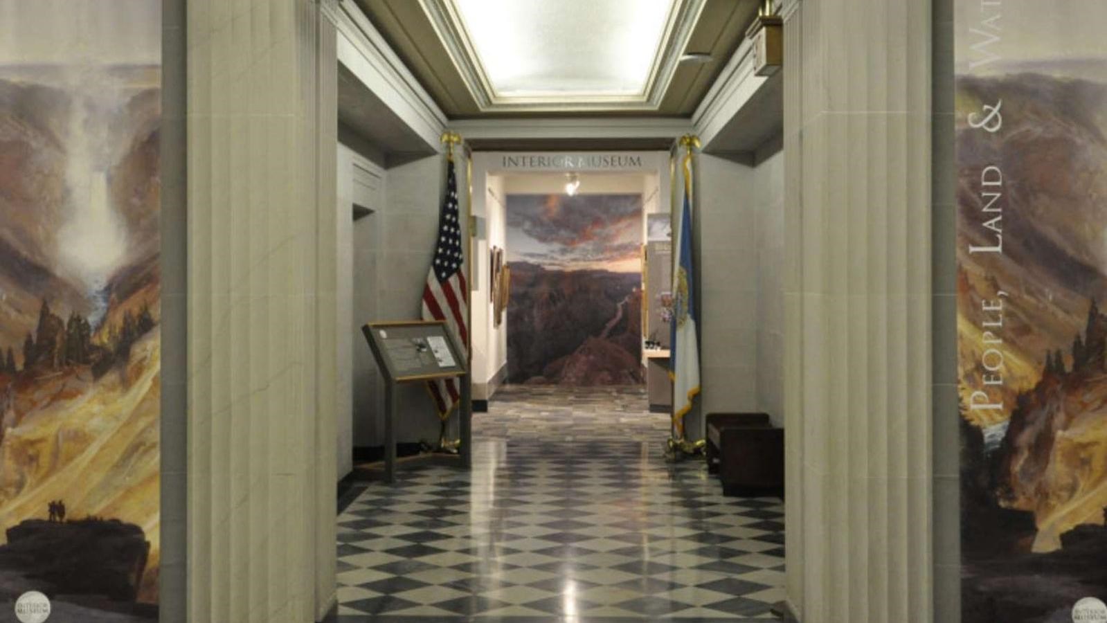 A entrance to a hallway. On either side of the entrance are murals with the words, 