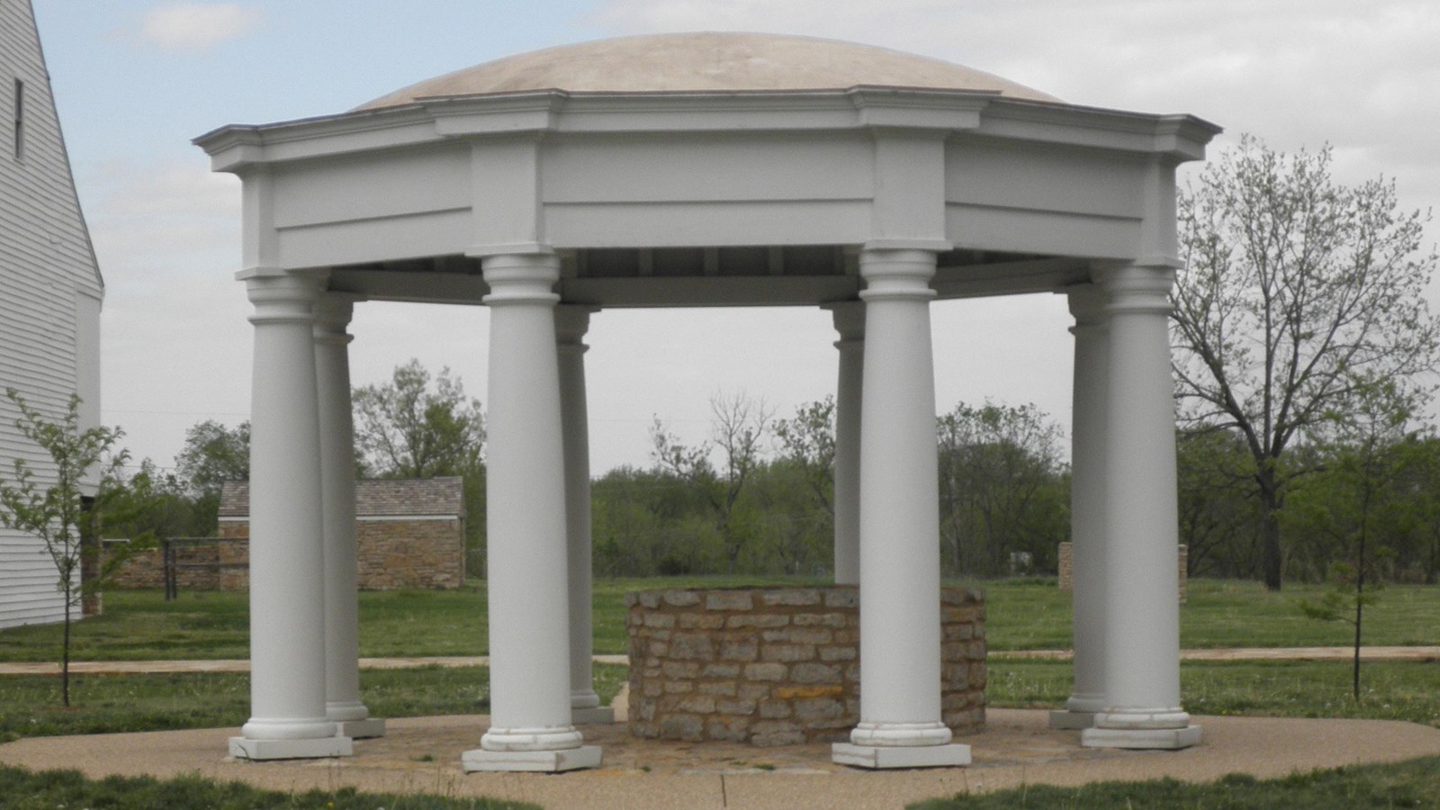 Circular white dome with white wooden pillars-stone well underneath canopy