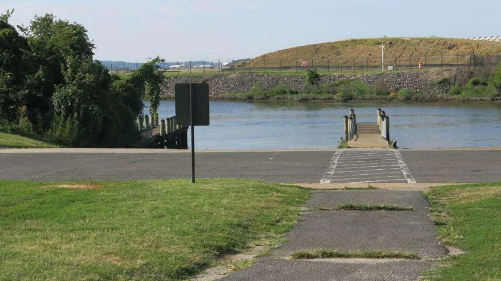 A boat launch leads to a narrow channel with a runway of National Airport behind it.