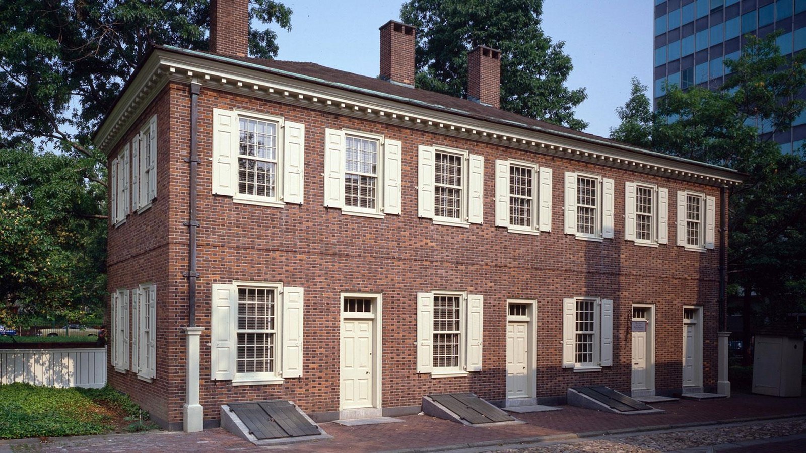 A color photo of a two story red brick building, rectangular in shape with rows of windows
