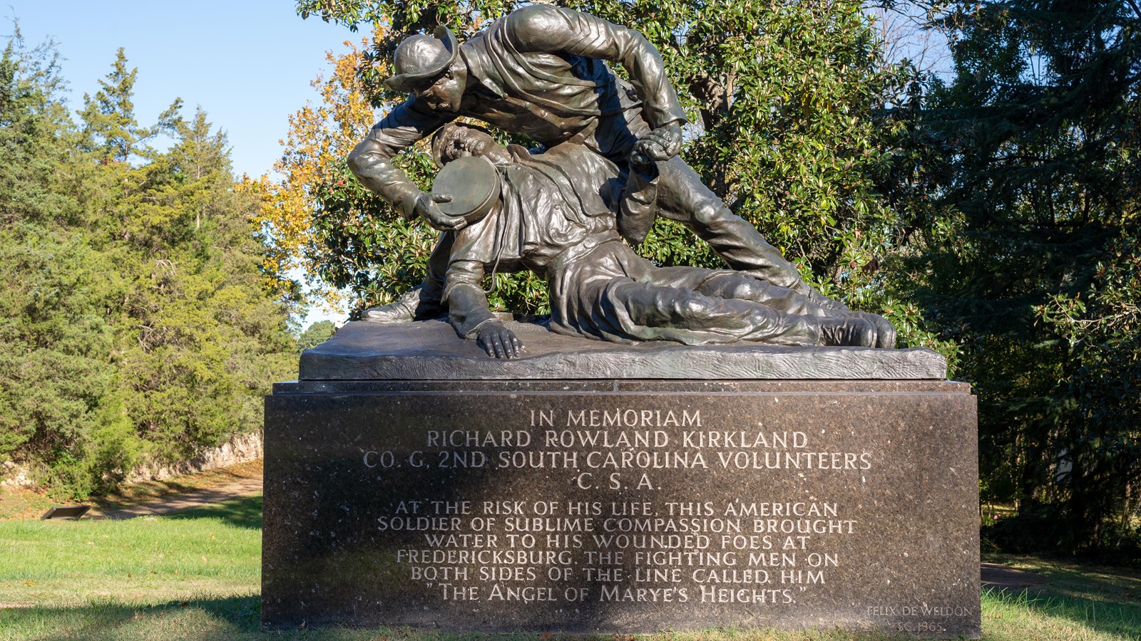 A 15ft tall statue of a soldier holder another in his arms and giving him water.