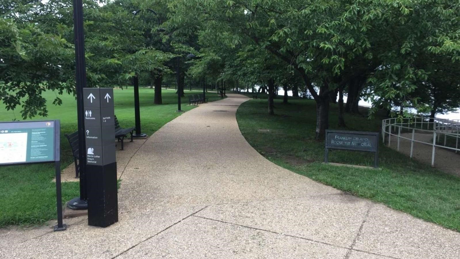Tree-lined, rock-covered path leads past Franklin Delano Roosevelt Memorial sign on the right.