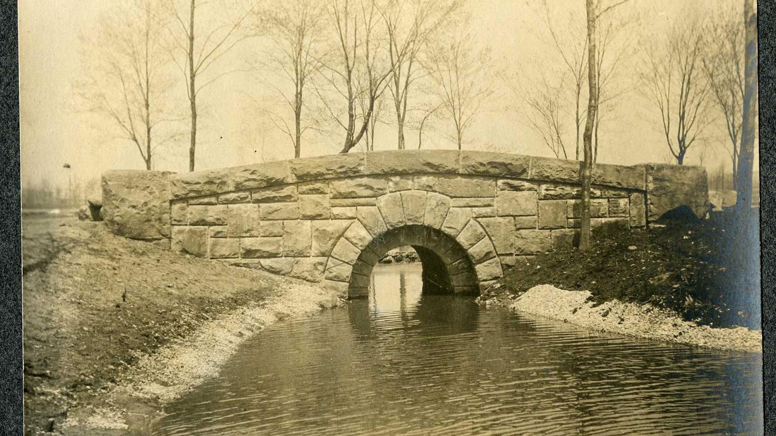Black and white of stone bridge with arch over water