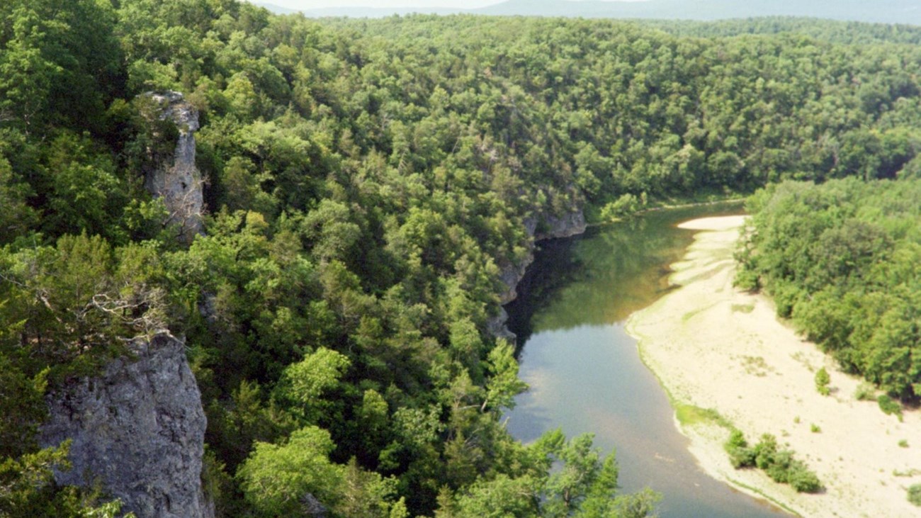view of river from above with green trees along both sides of the water