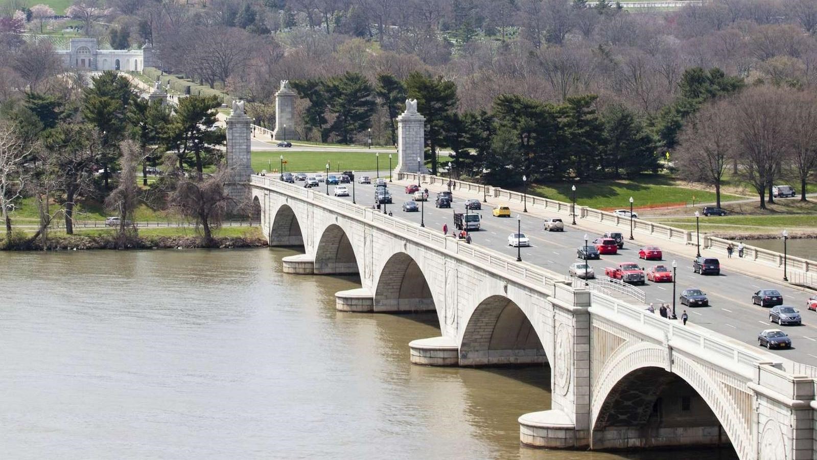 Arlington Memorial Bridge crosses over the Potomac, several cars drive across it.