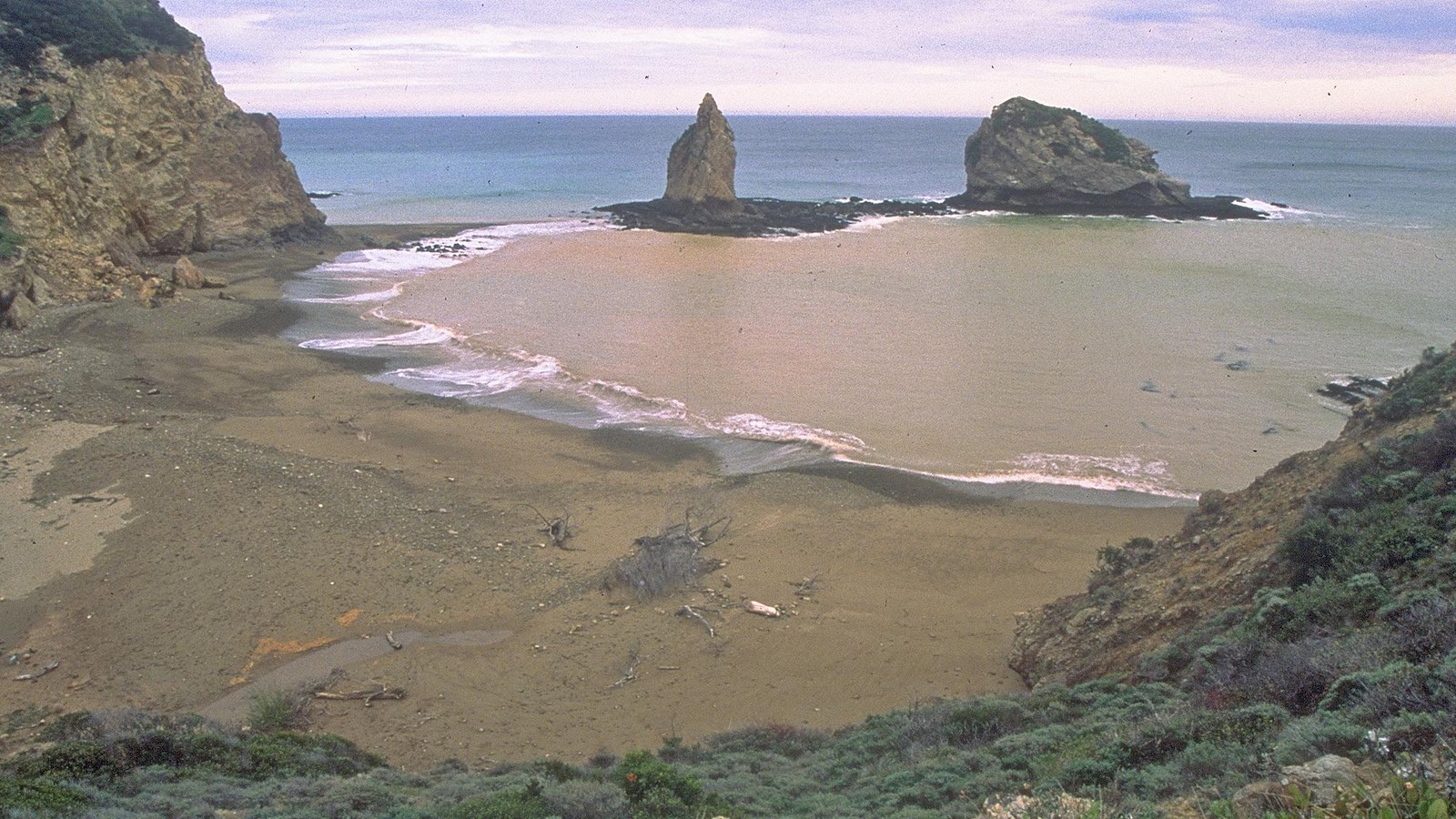 protected anchorage with sandy beach and rocks offshore