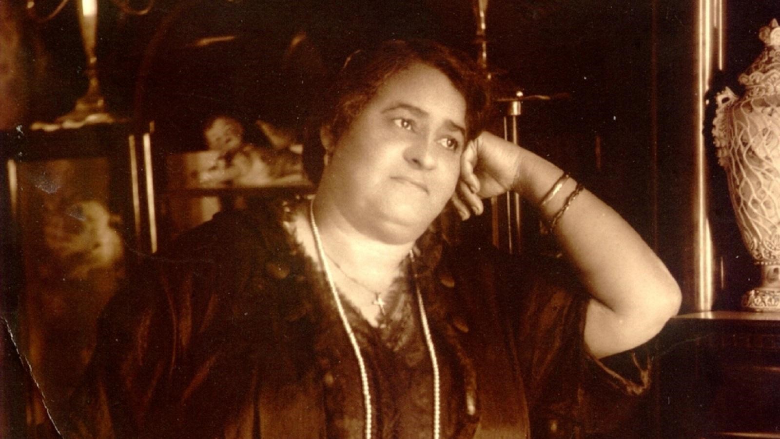 Maggie L. Walker leaning in a dark dress and pearl necklace on