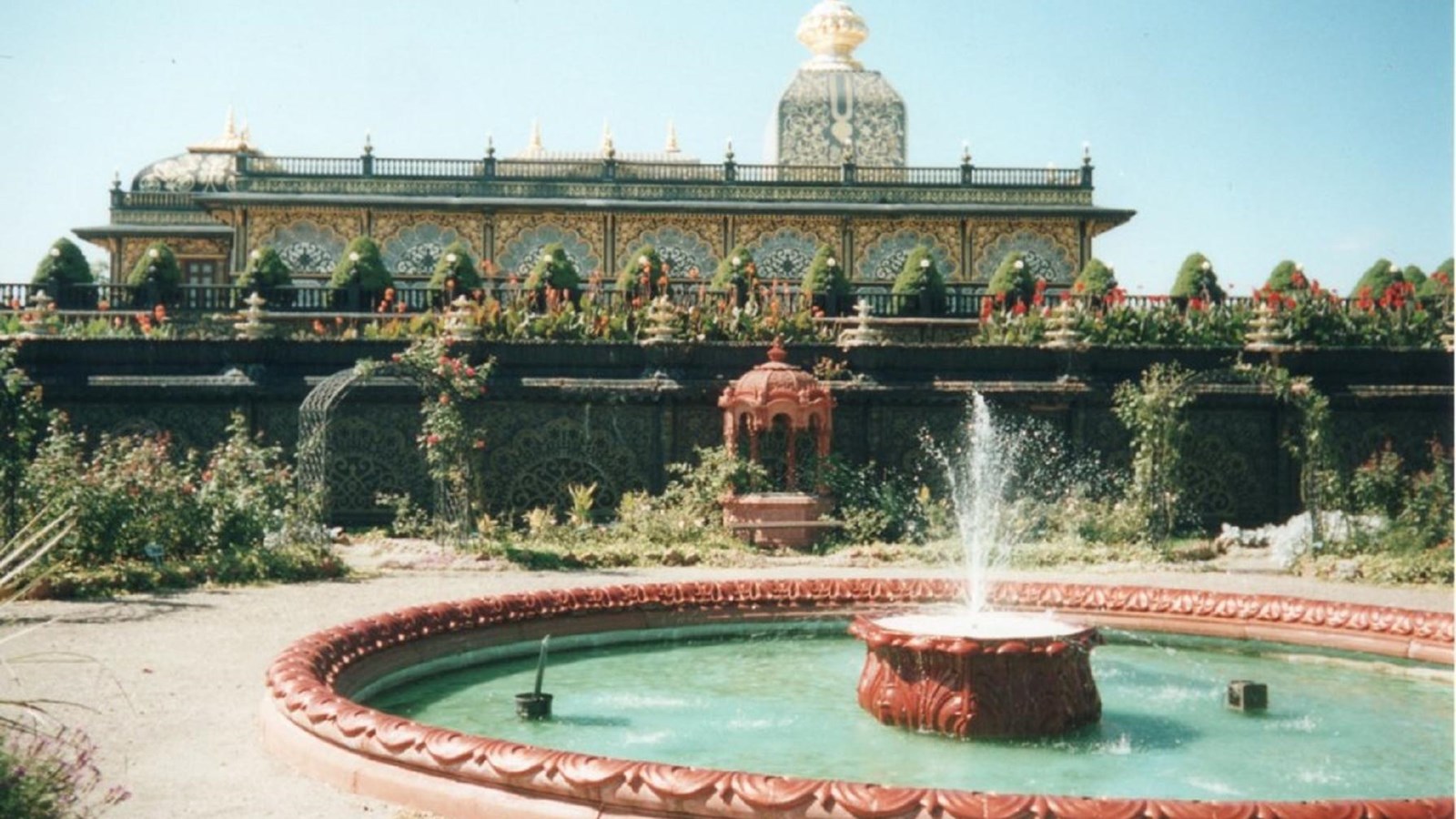 A circular fountain sits in front of an ornate Southeast Asian style building