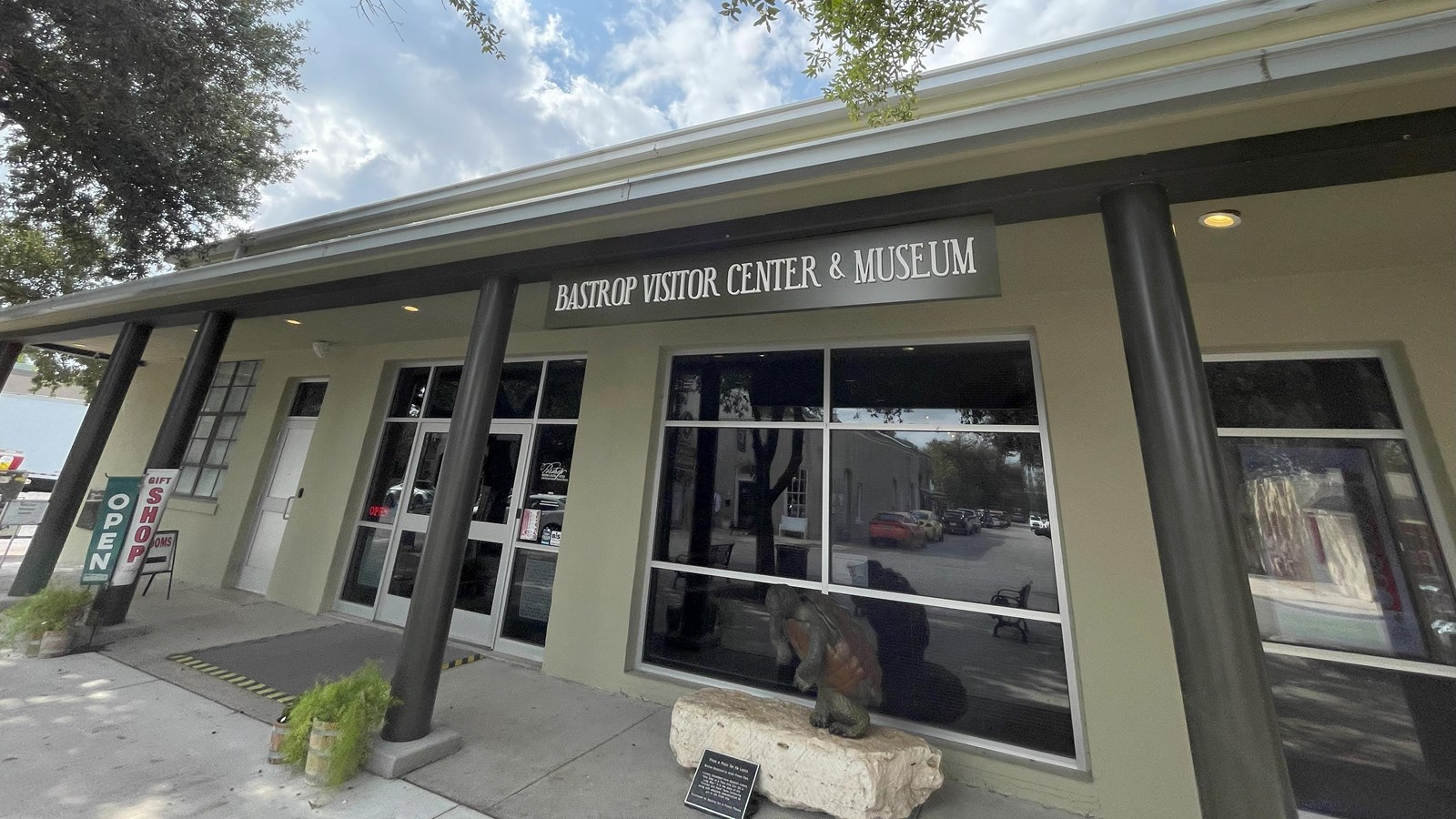The outside of a single-story building, with a window front, along a sidewalk.