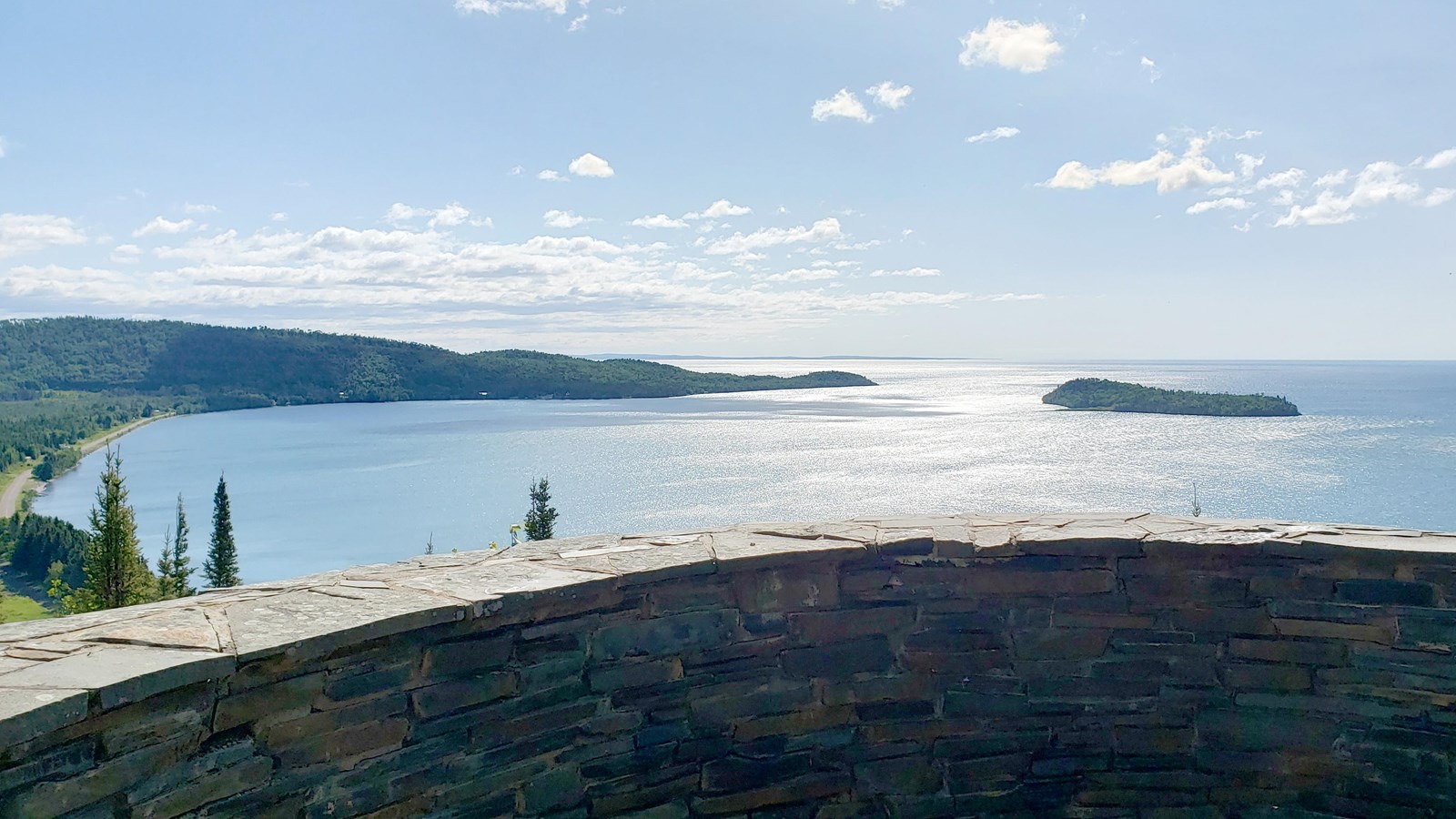 A low stone wall viewpoint into a bay with a peninsula and island.
