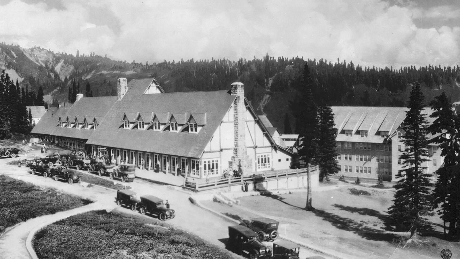 A black and white photo of a large wooden building with a steeply-pitched roof.