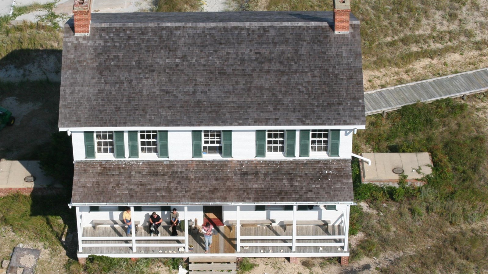2 story white house with green shutters seen from the top of the lighthouse