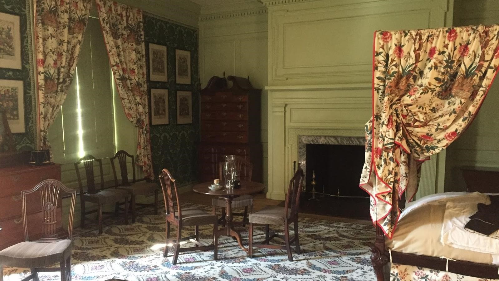 A brightly painted room with a large, 4-post bed and elaborate draperies. 