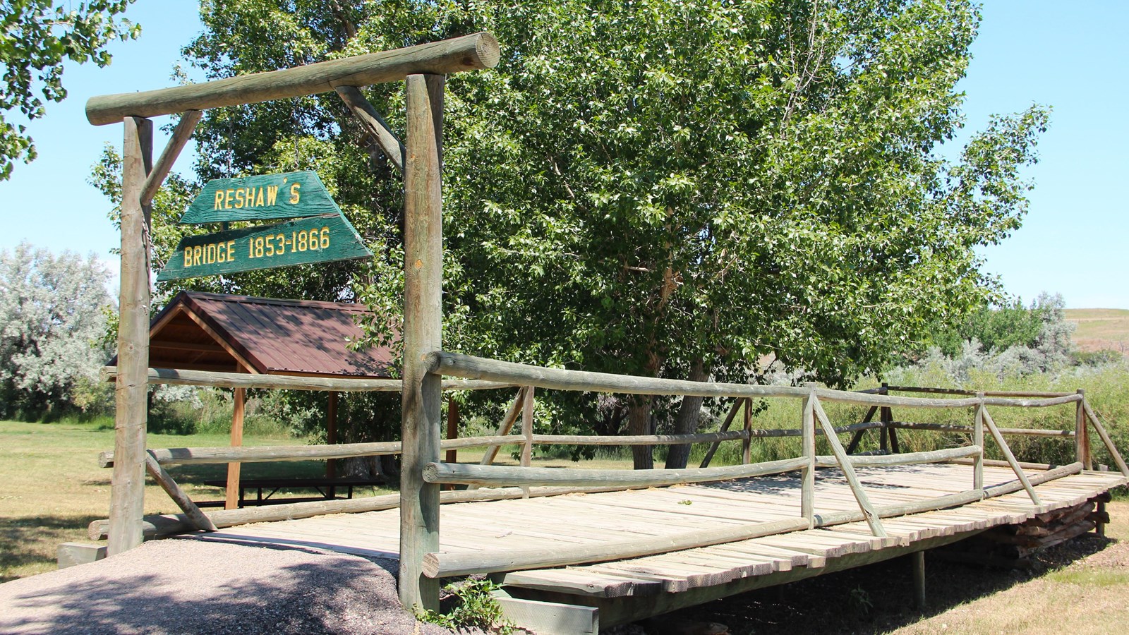 Short replica of the original 19th‑century structure bridge with posts, planks, and signage.