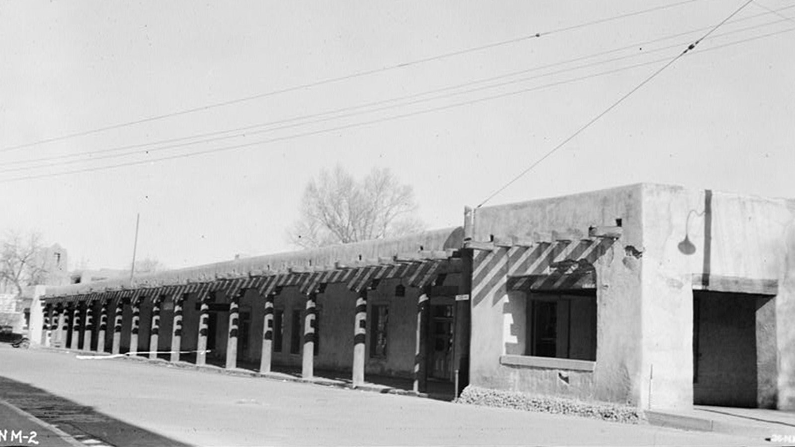 A long, one-story adobe building with pillars